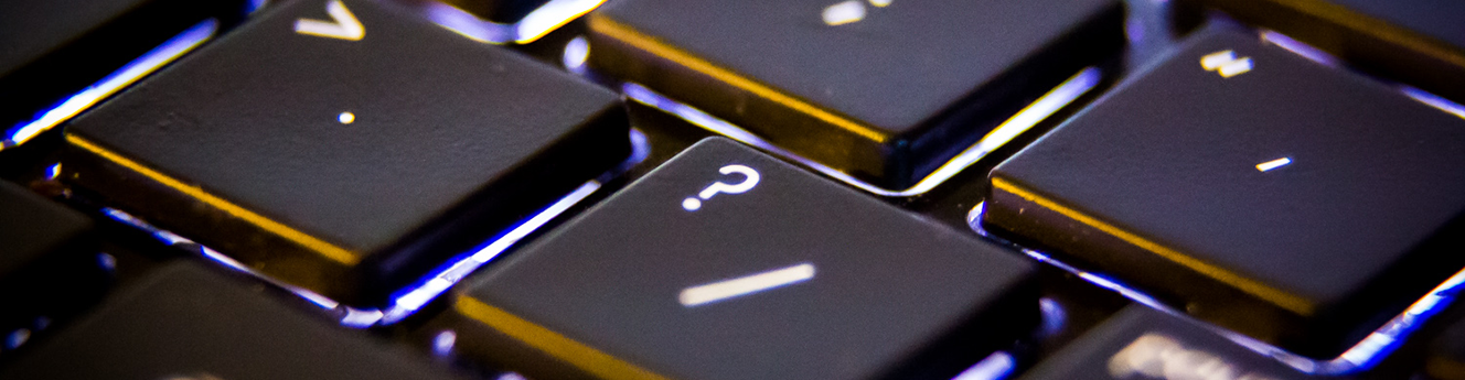 Detail of a black computer keyboard, focusing on the question mark key