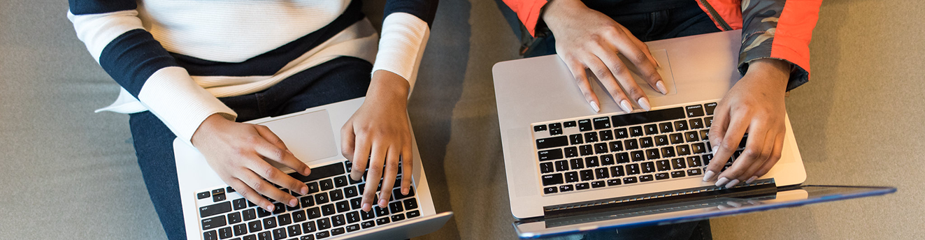 Two women of color typing on their laptops